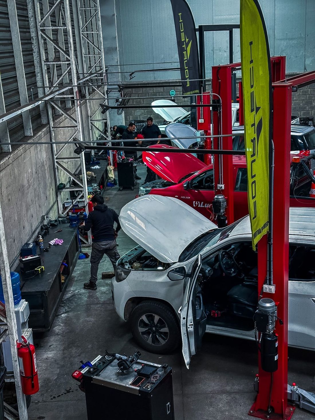 Equipo de mecánicos trabajando en camionetas y autos en el servicio técnico automotriz Fourtech, Quilicura